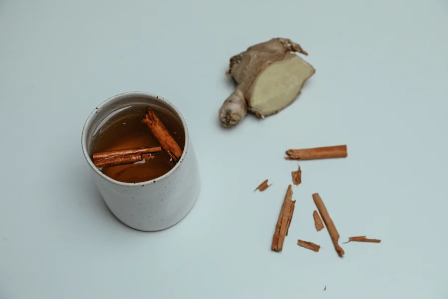 Tasse de décoction de cannelle avec un morceau de gingembre frais et des bâtons de cannelle